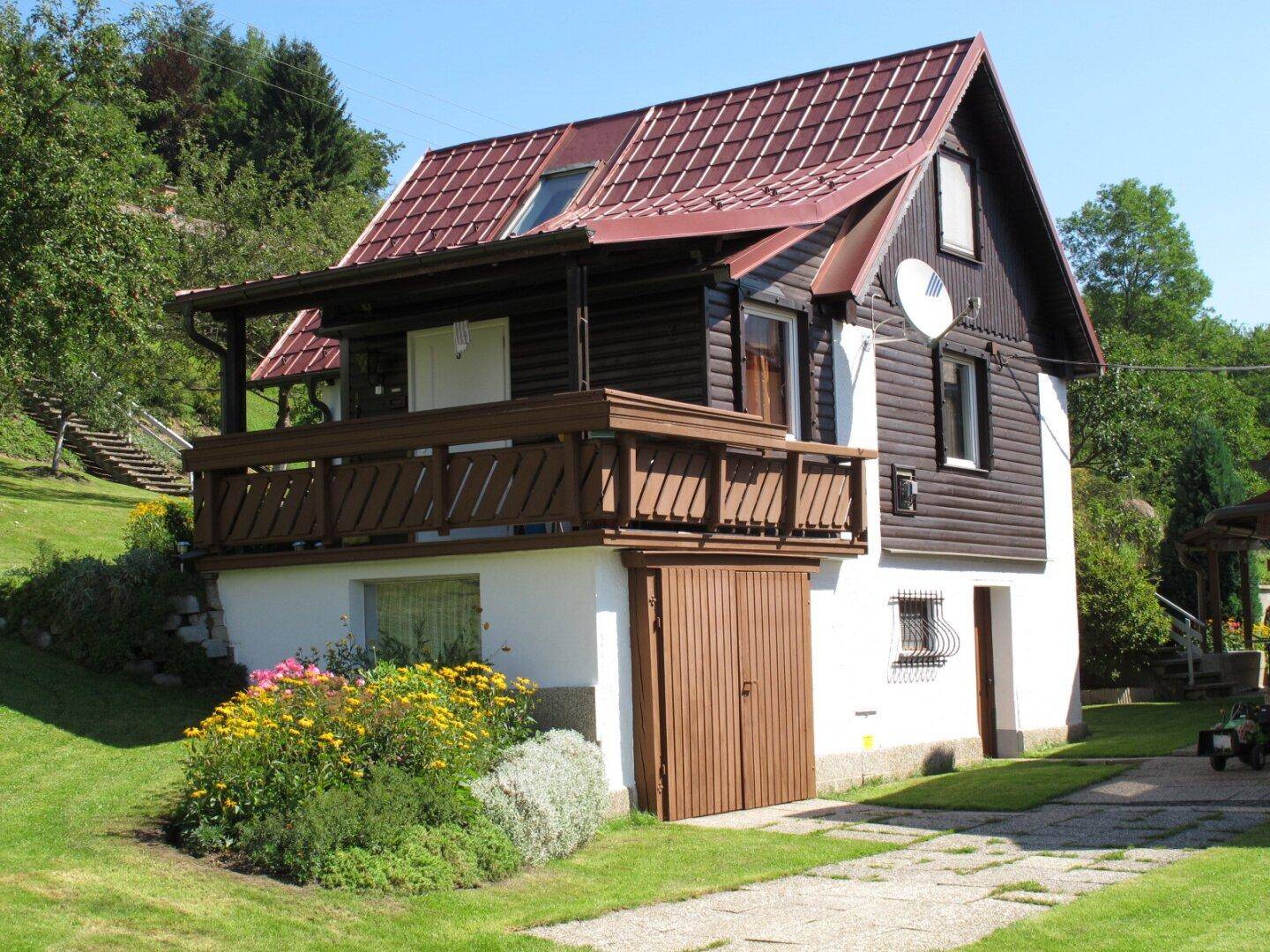 Rustikales Holzhaus mit großem Balkon, der einen schönen Blick ins Grüne bietet.