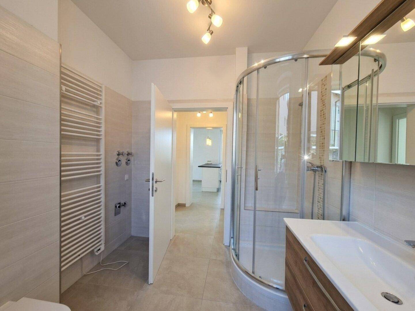 Modernes Badezimmer mit Eckdusche, Einzelwaschbecken und beheiztem Handtuchhalter.
