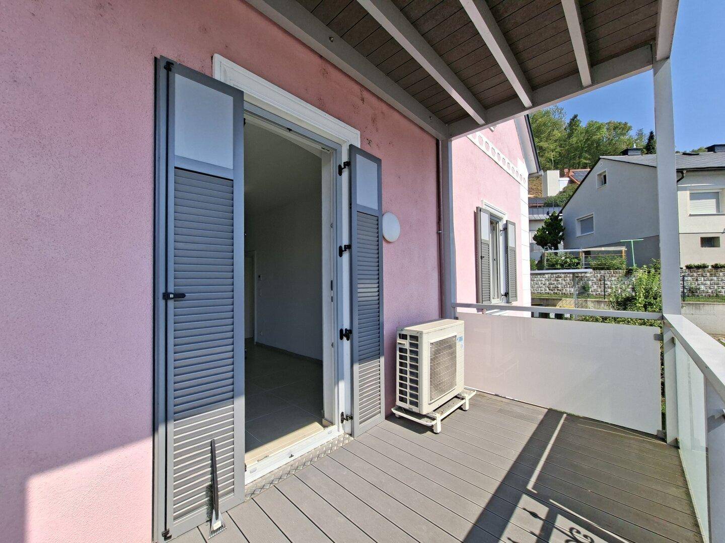 Geräumiger Balkon mit Holzdecking und Klimaanlage, ideal für entspannte Stunden im Freien.