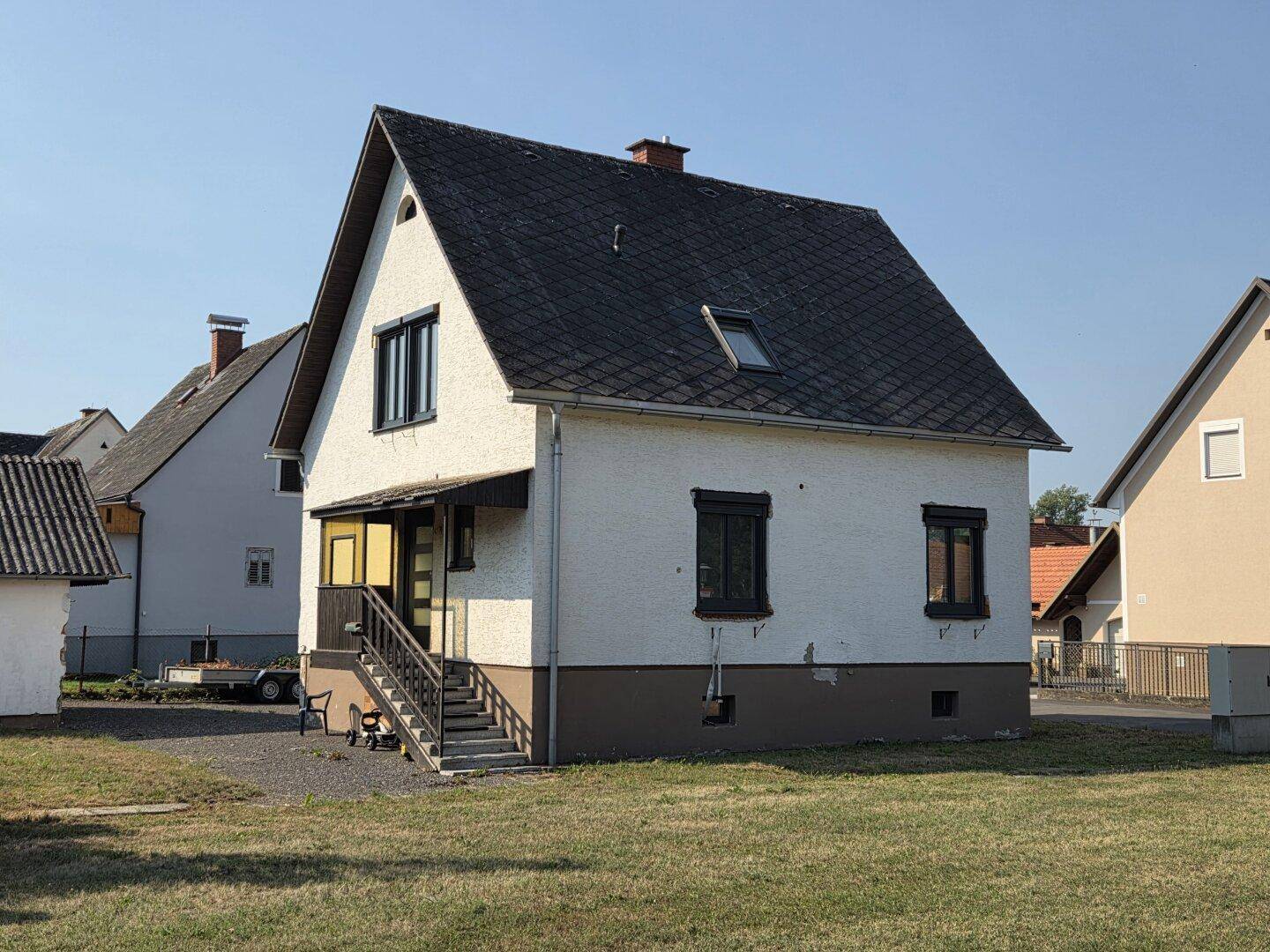 Rückansicht eines Einfamilienhauses mit Satteldach, kleinem Vordach und Gartenbereich.