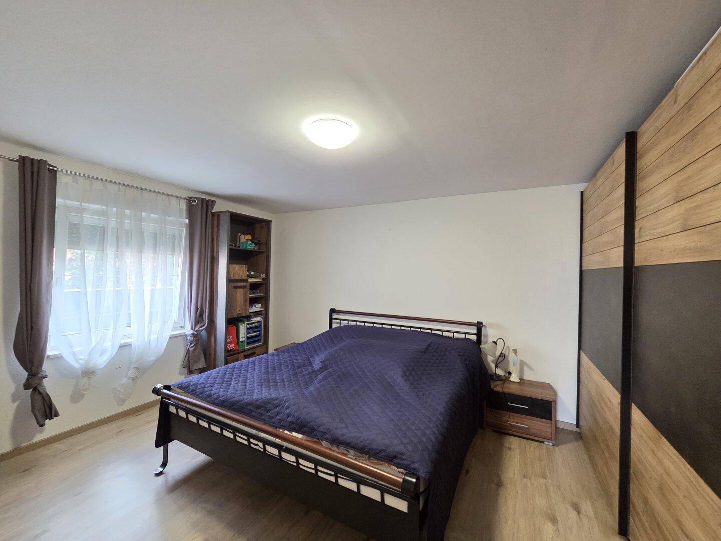 Schlafzimmer mit Doppelbett, Holzfußboden und großem Kleiderschrank.