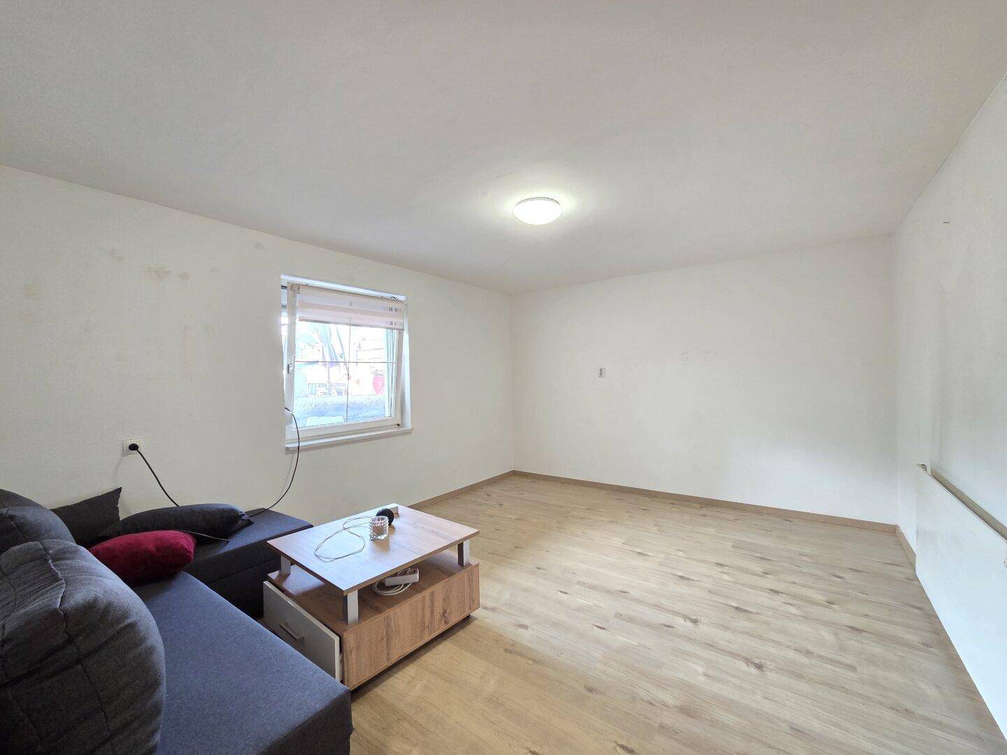 Geräumiges Wohnzimmer mit Sofa, Couchtisch und Holzfußboden.