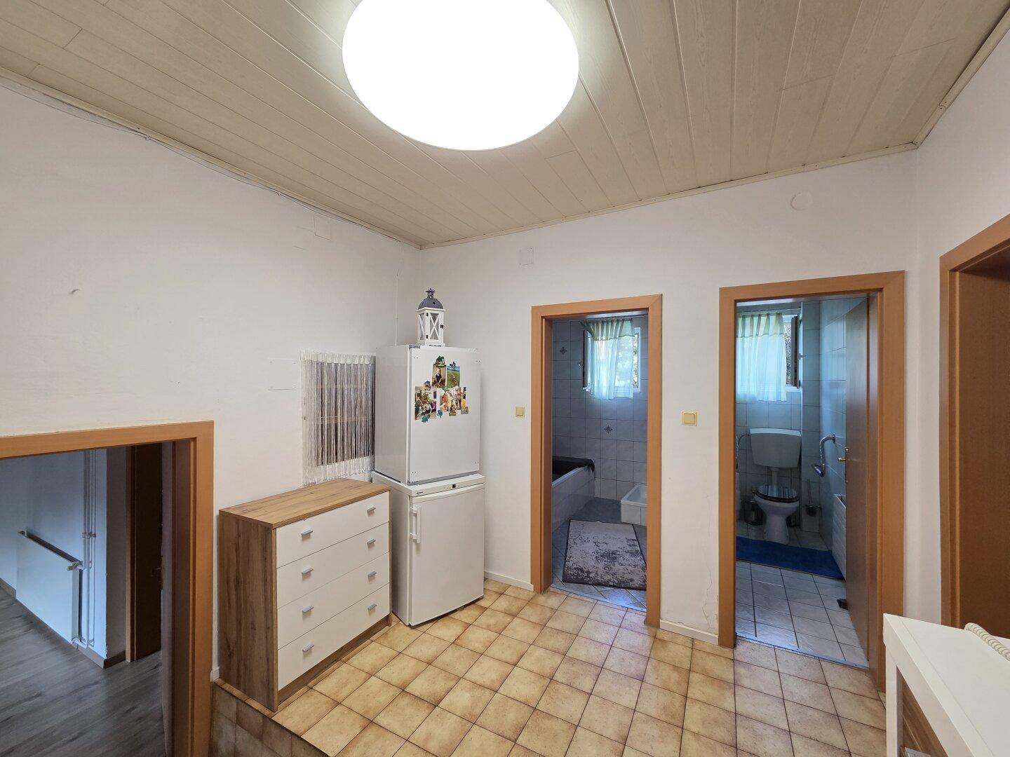 Bereich mit Kühlschrank und Zugang zu Badezimmer und separatem WC.