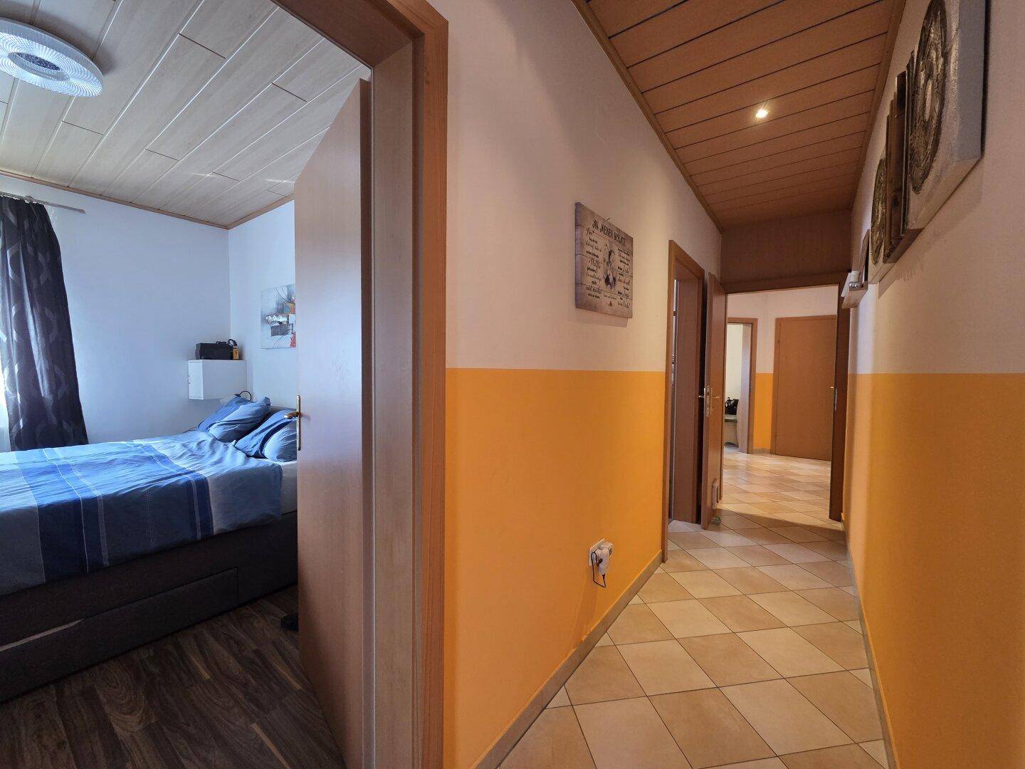 Langer Flur mit Fliesenboden, Holzdecke und Zugang zu mehreren Zimmern.