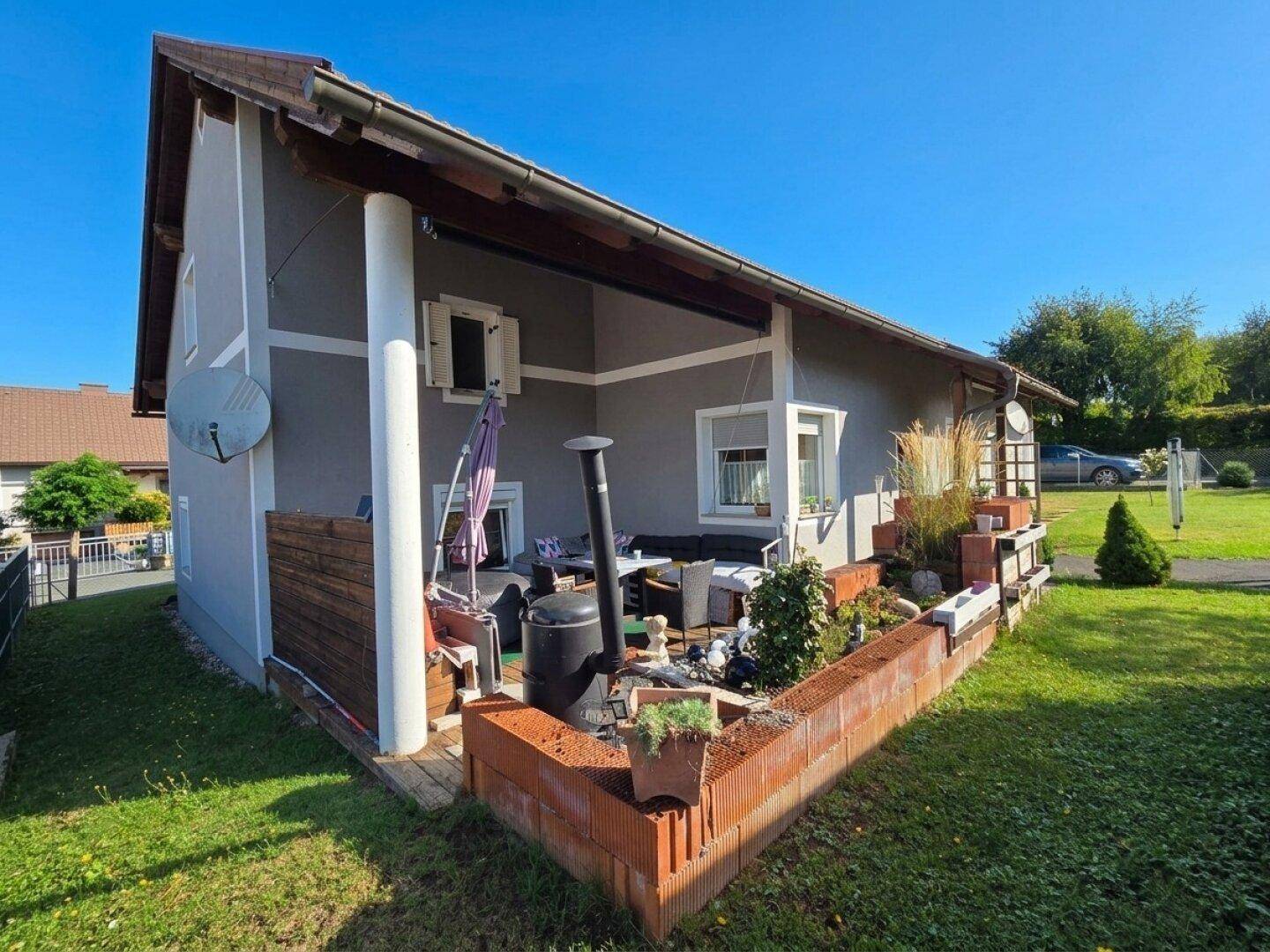 Gemütliche Terrasse mit Sitzgelegenheiten und Pflanzen in Ziegelbeeten.