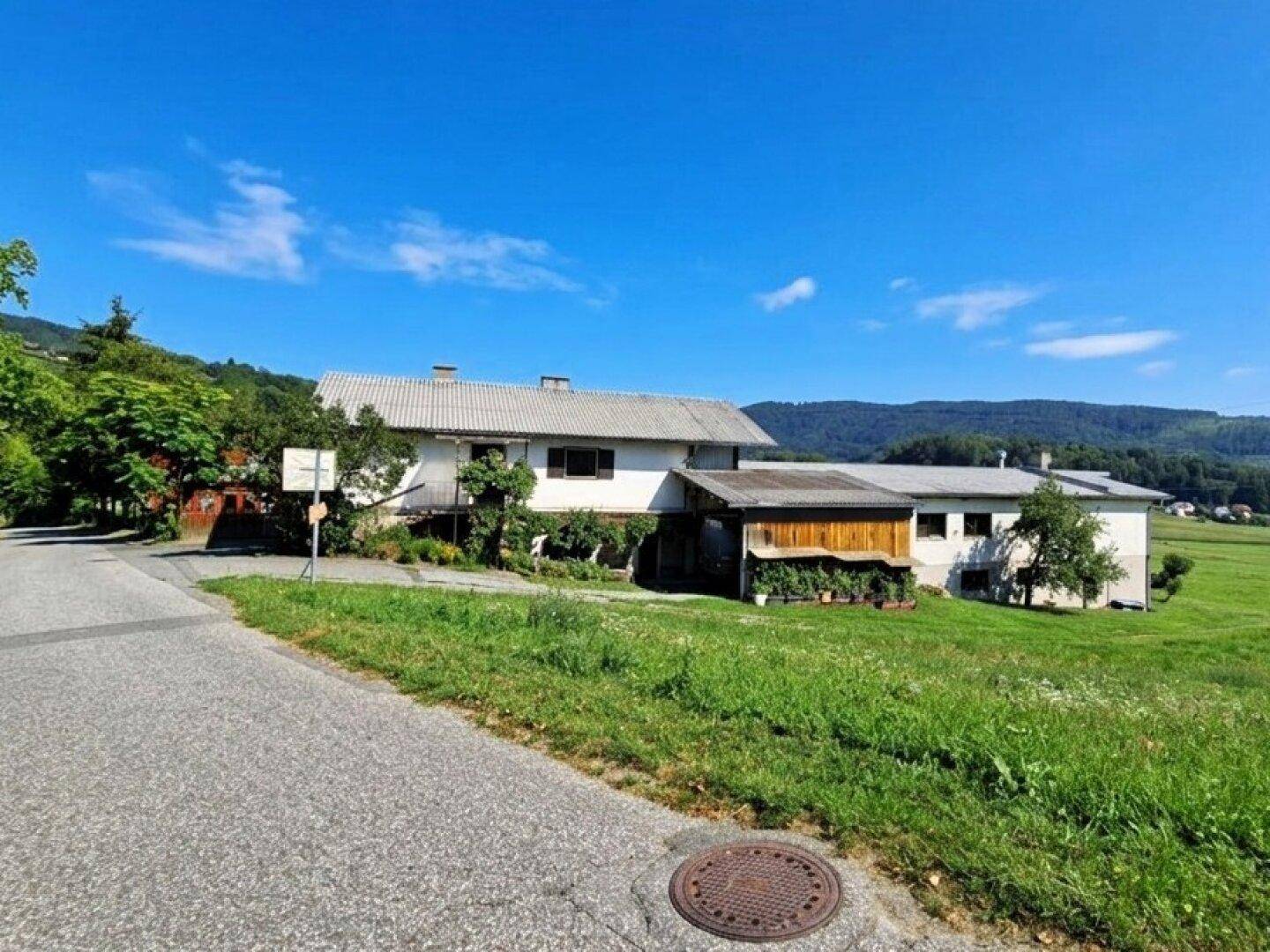 Anwesen in ländlicher Lage mit weiten Feldern und blauem Himmel an einem sonnigen Tag.