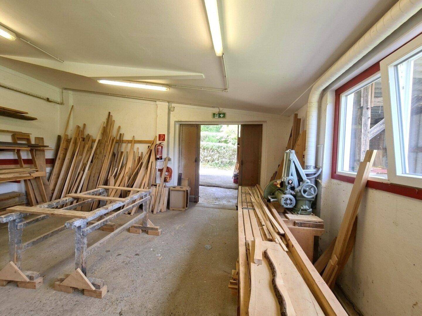 Werkstattraum mit Holzmaterialien und Maschinen, ideal für handwerkliche Tätigkeiten.