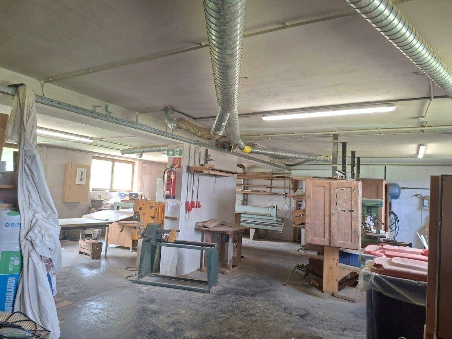 Industrieller Werkstattraum mit Lüftungsrohren, Maschinen und viel Stauraum.
