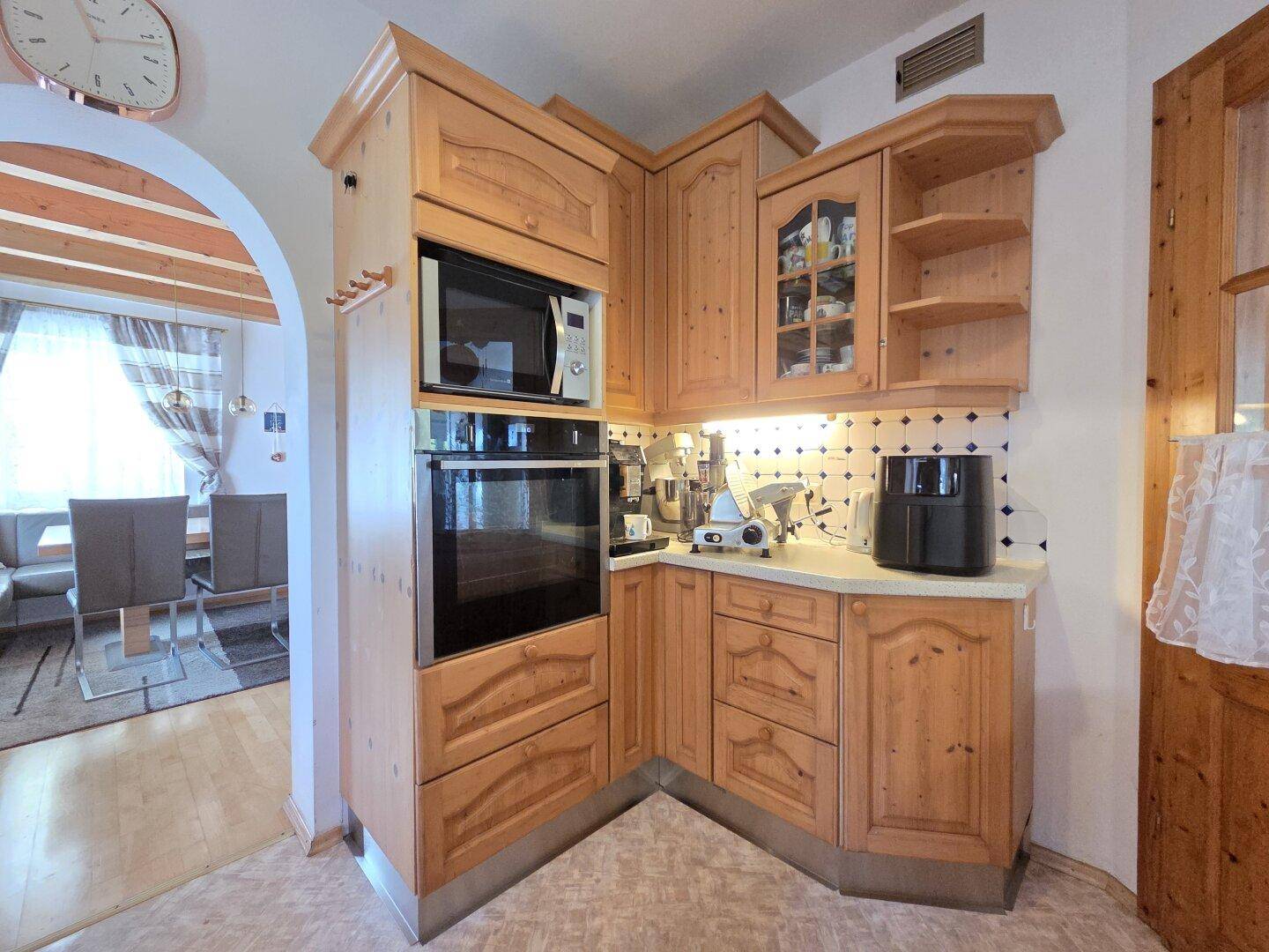 Gemütliche Holzküche mit integriertem Backofen und Mikrowelle, offen zum Essbereich.