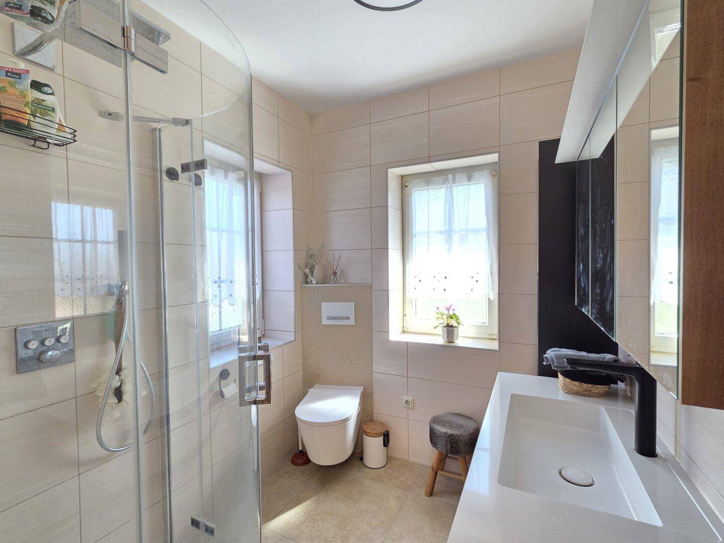 Modernes Badezimmer mit begehbarer Dusche, Wand-WC und Fenster für Tageslicht.