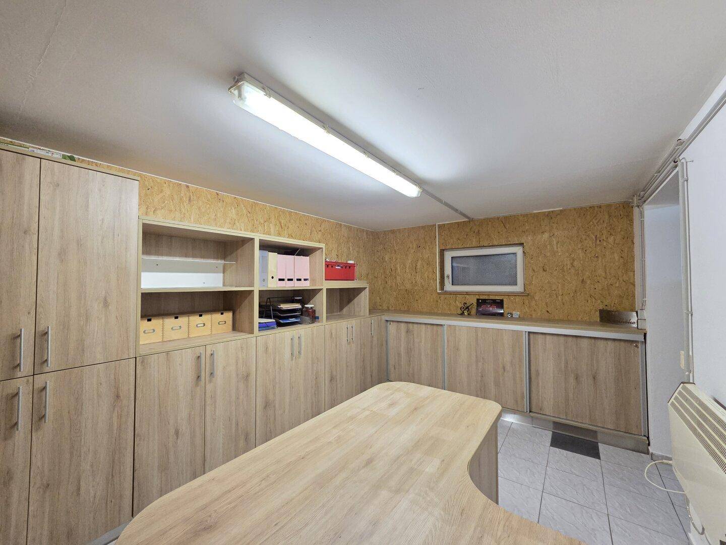 Geräumiger Arbeitsraum im Untergeschoss mit Holzverkleidung und praktischen Regalen.