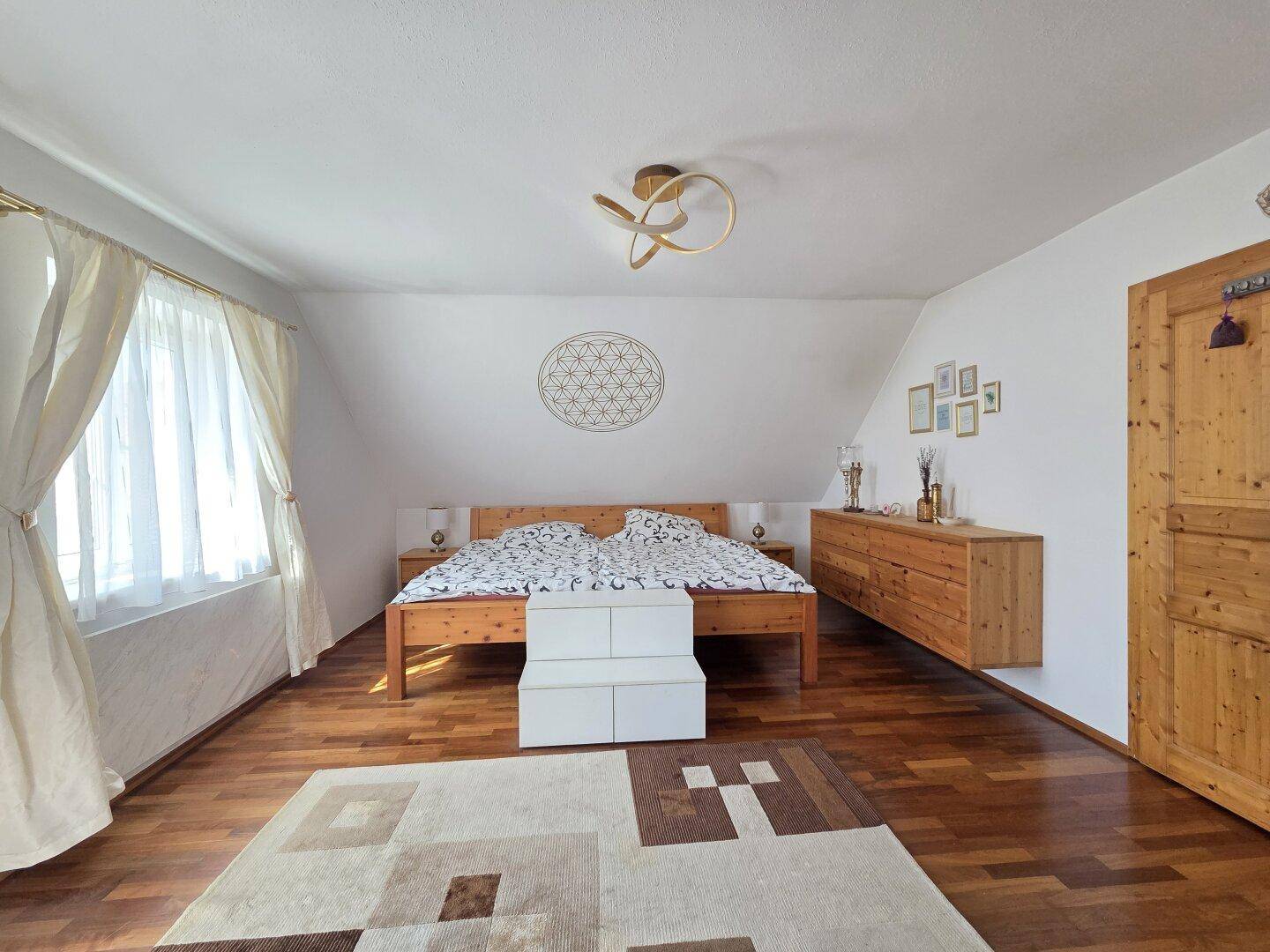 Helles Schlafzimmer mit Holzbett, Parkettboden und Dachschräge.