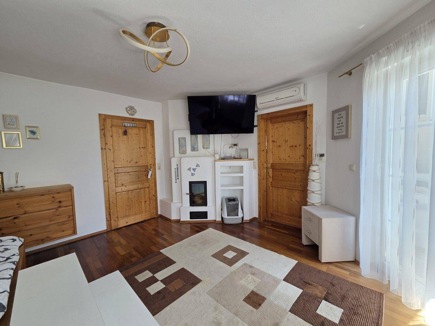 Schlafzimmer mit Holzboden, Kachelofen und Zugang zu einem Balkon oder Terrasse.