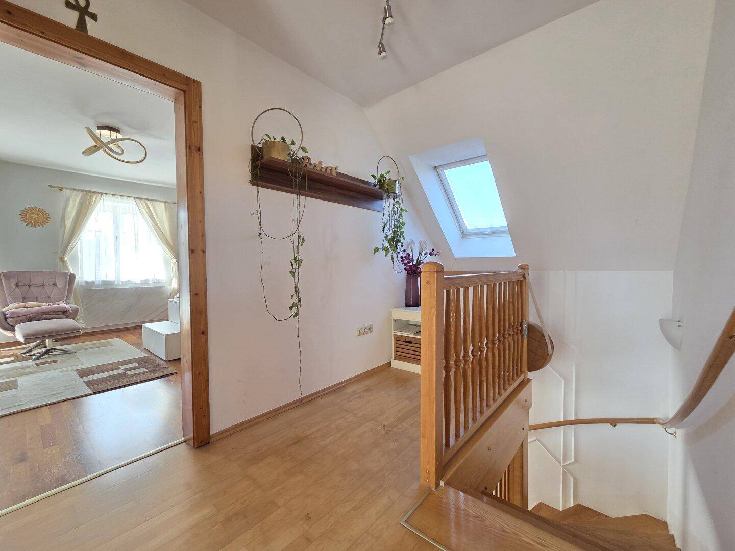 Heller Flur im Obergeschoss mit Holztreppe, Dachfenster und Blick in den Wohnbereich.