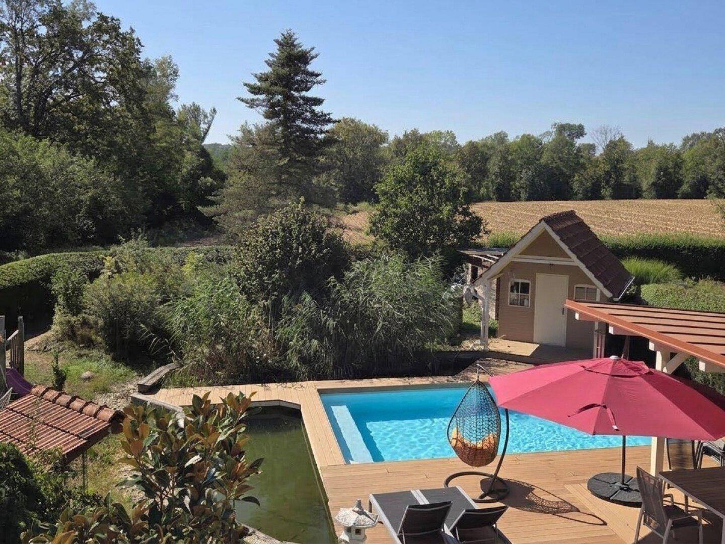 Großer Garten mit Pool, Holzdeck, Teich und weitem Blick in die Natur.
