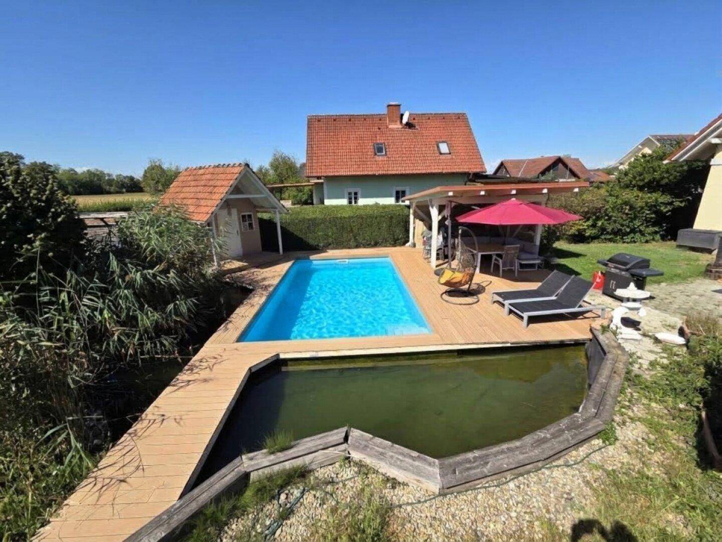 Weitläufiger Garten mit Pool, Holzdeck, Teich und Blick auf das Einfamilienhaus.