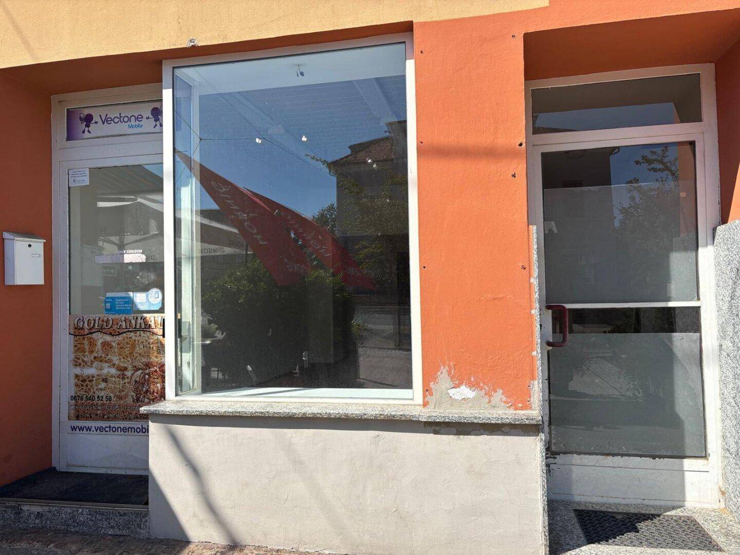Eingangsbereich eines Geschäfts mit großer Schaufensterfront und Glastür zur Straße hin.