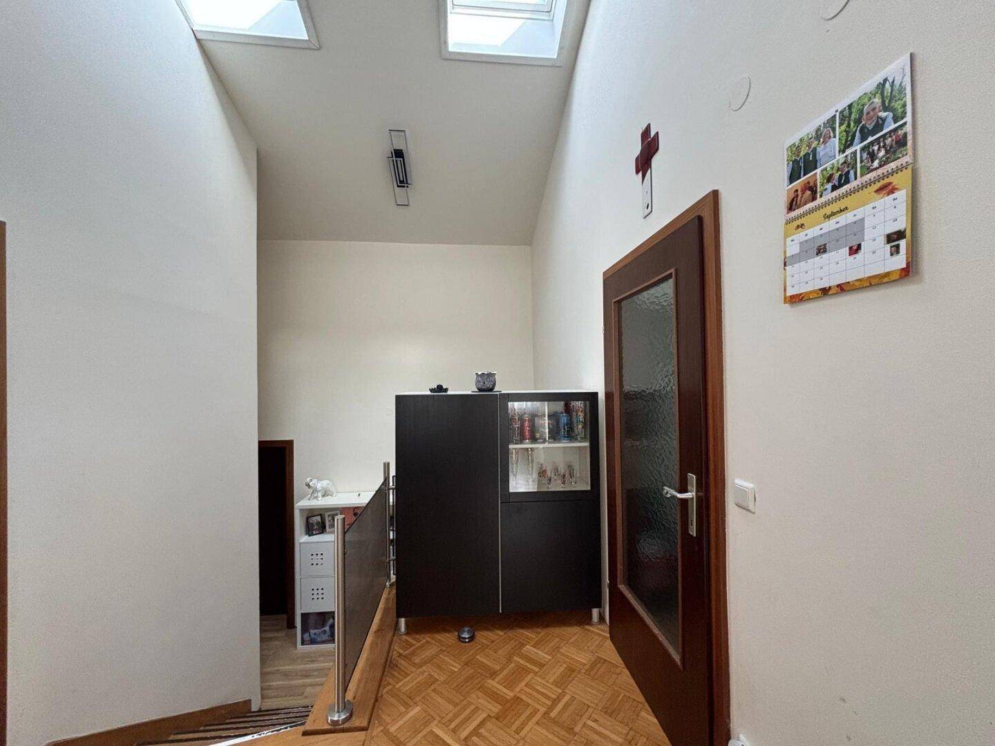 Lichtdurchfluteter Flur mit Oberlichtern, Holzboden und Zugang zu weiteren Räumen.
