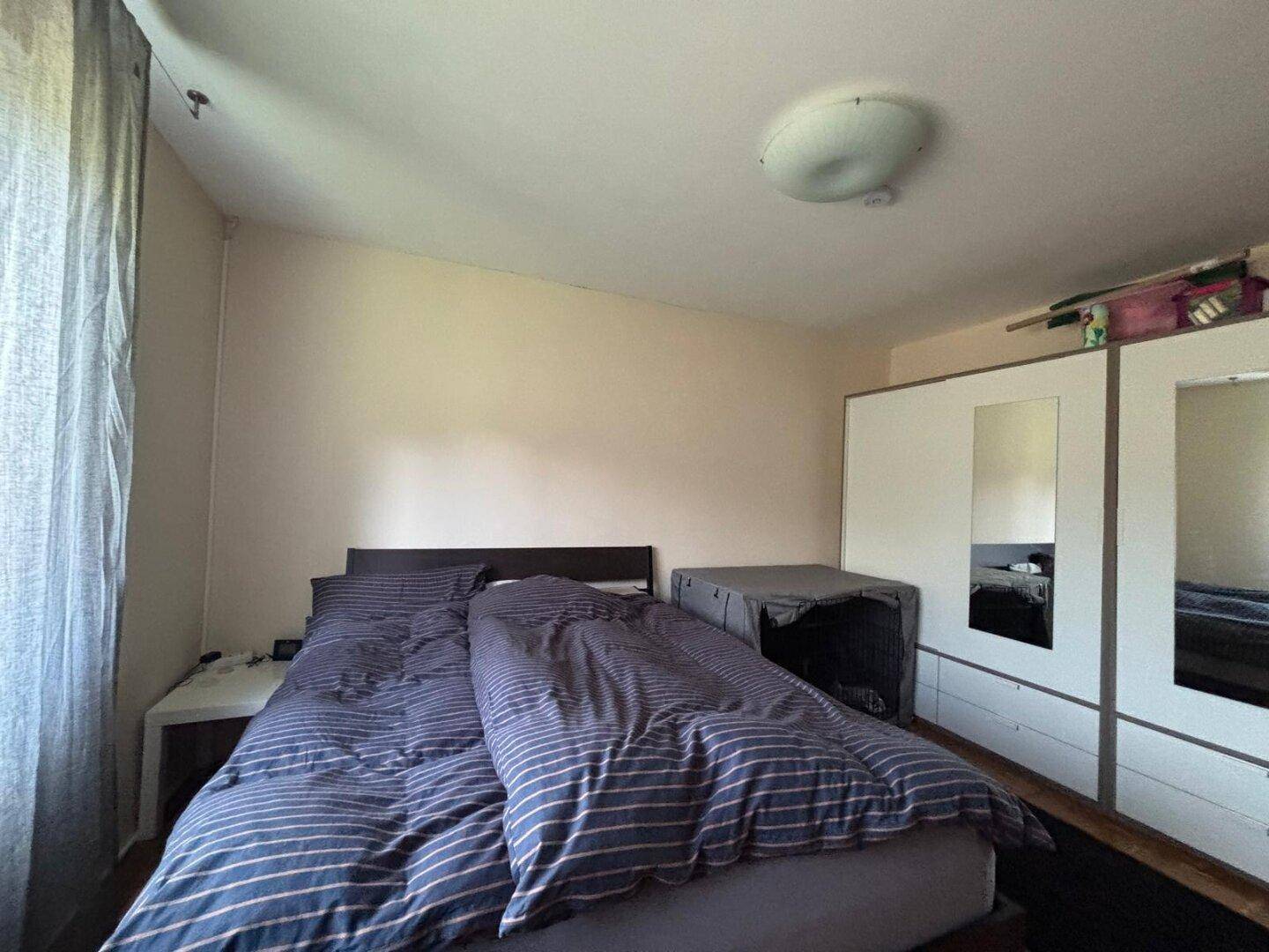 Schlafzimmer mit Doppelbett, großem Kleiderschrank und schlichter Einrichtung.