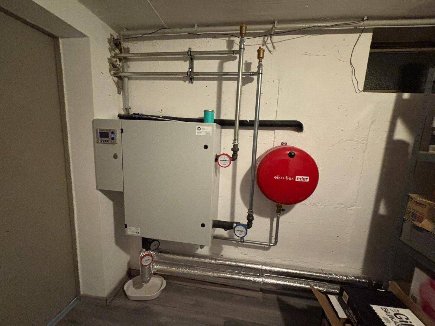 Heizungsraum im Keller mit moderner Heizungsanlage und Warmwasserspeicher.
