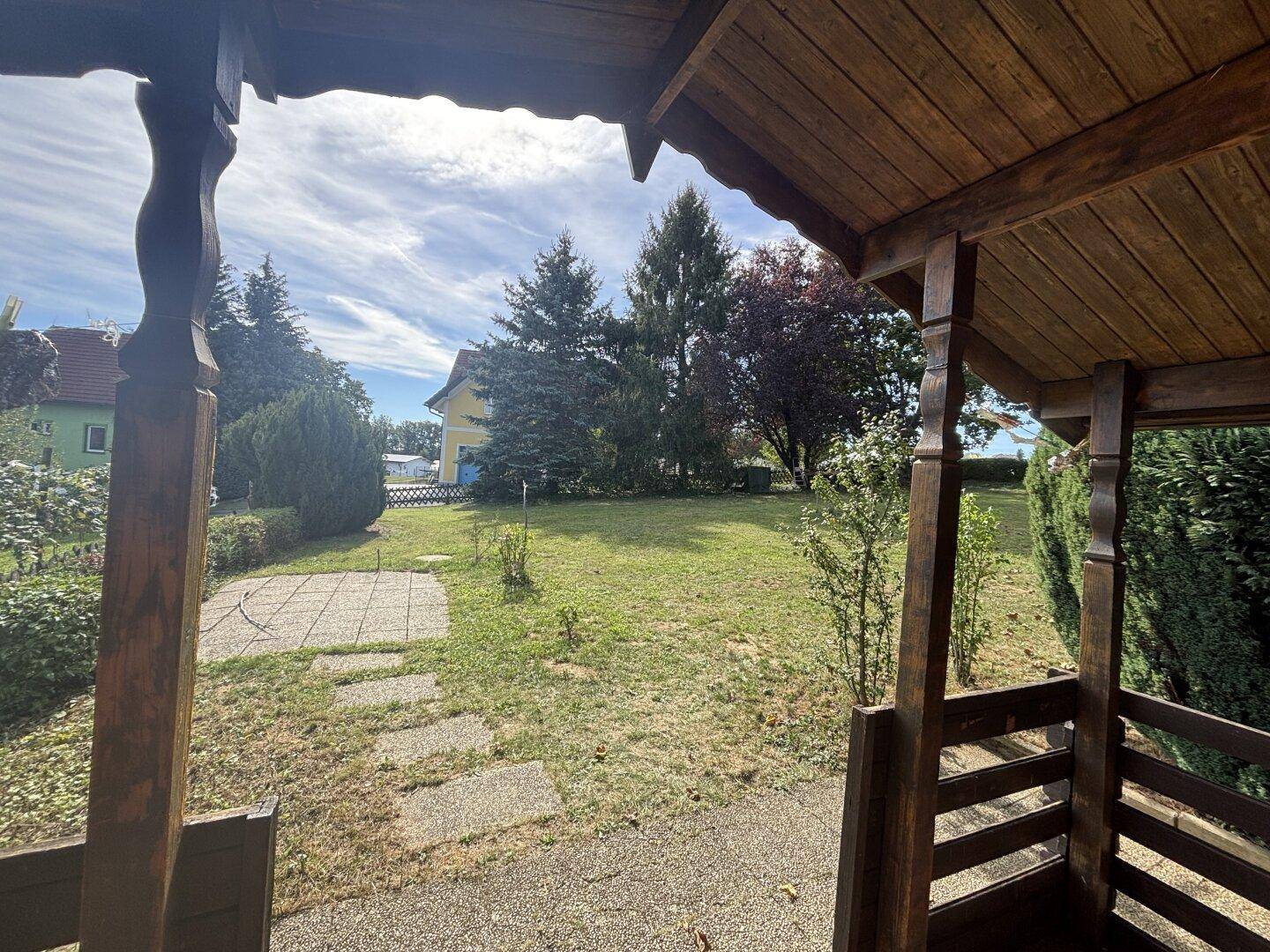 Blick aus einem Holzschuppen auf die Rasenfläche des Gartens und die umliegende Wohnbebauung.