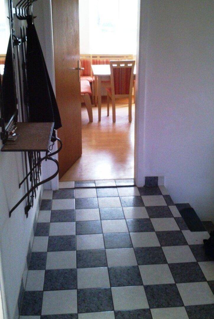 Eingangsbereich mit schwarz-weiß gefliestem Boden und Blick in den angrenzenden Essbereich.