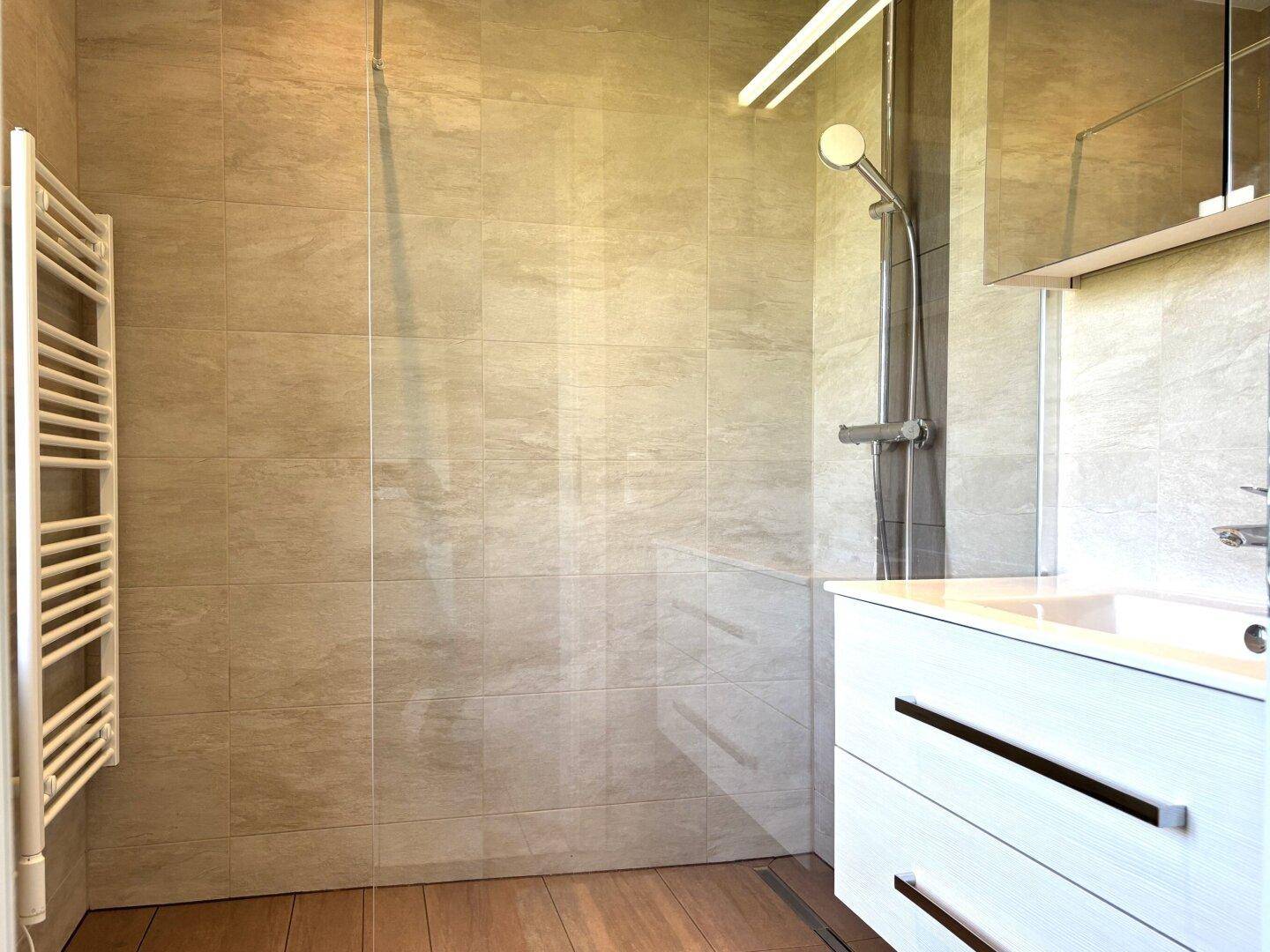 Modernes Badezimmer mit ebenerdiger Dusche, Einzelwaschbecken und Handtuchheizkörper.