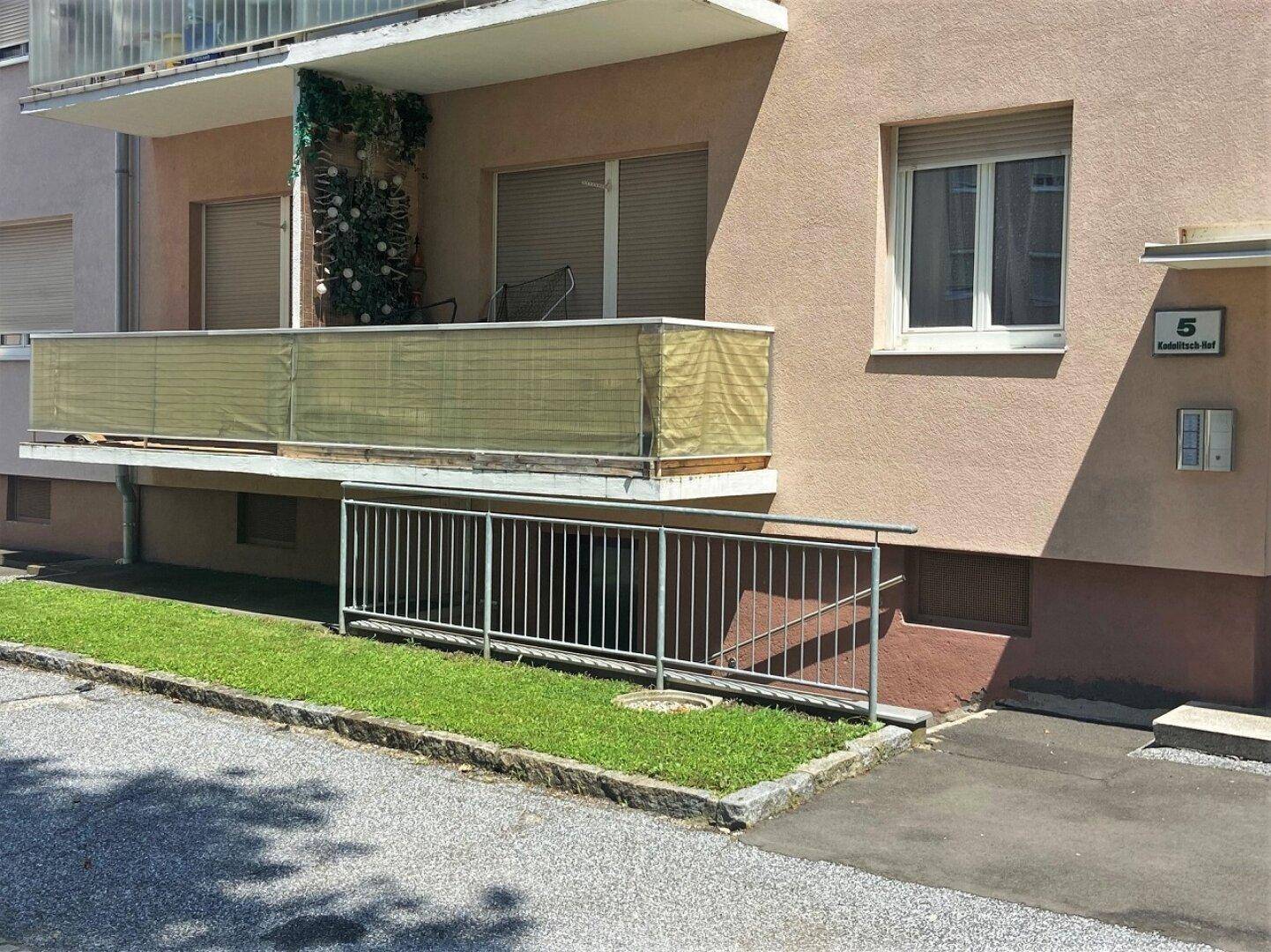 Gebäudefassade mit Balkon und barrierefreiem Zugang über eine Rampe.
