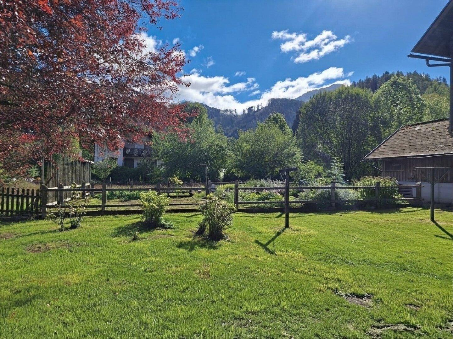 Gepflegter Gartenbereich mit Holzzaun und Blick auf die umliegende Berglandschaft.