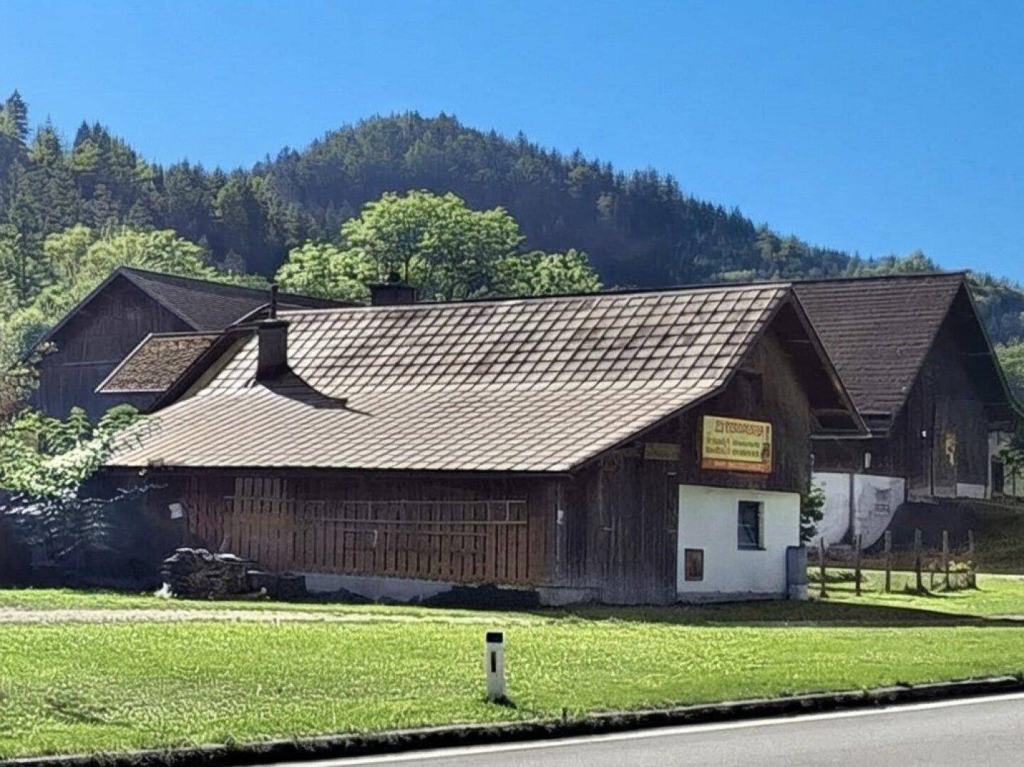 Rustikales Wirtschaftsgebäude mit Holzwänden und Satteldach in ländlicher Umgebung.