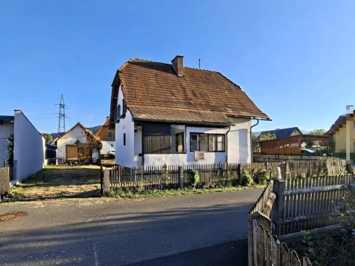Ansicht des Einfamilienhauses von der Straßenseite mit Holzzaun und Satteldach.