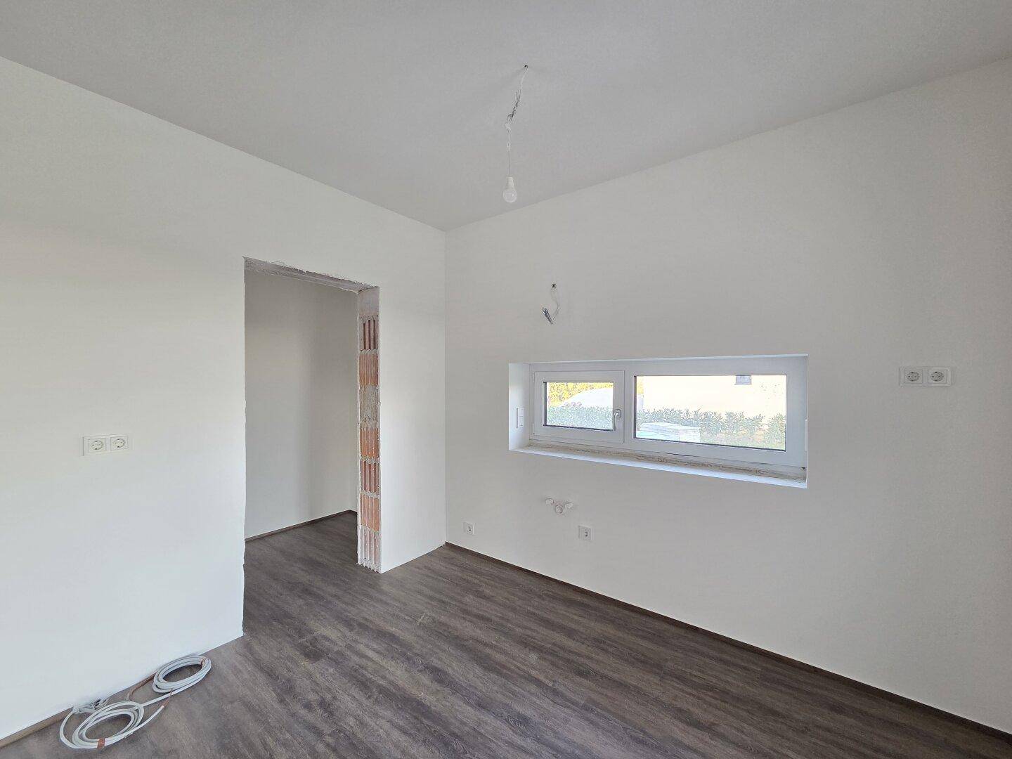 Leerer Raum mit weiß gestrichenen Wänden und einem Fenster, bereit für den Innenausbau.