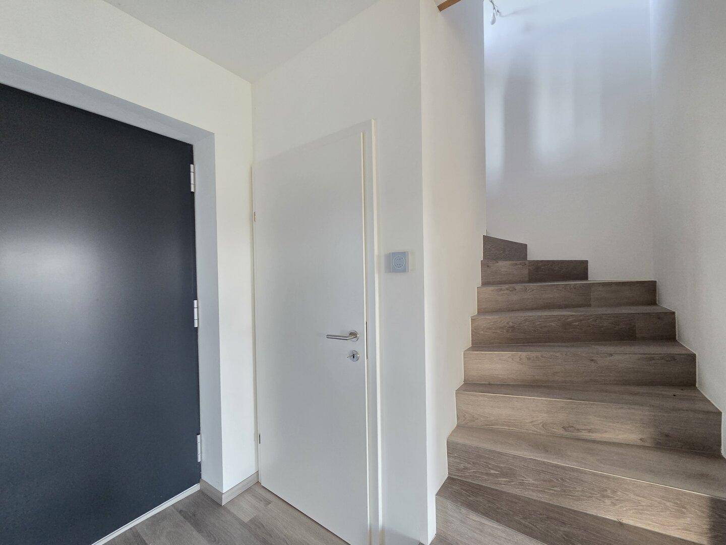Eingangsbereich mit Treppe und zwei Türen, die zu verschiedenen Räumen führen.