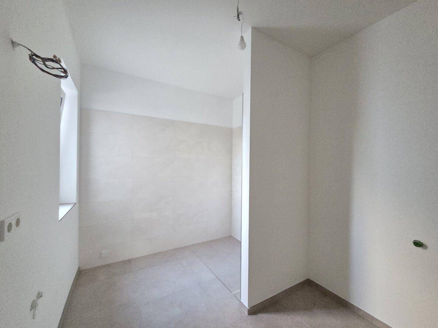 Unfertiges Badezimmer mit gefliesten Wänden und Boden, bereit für die Installation der Sanitärobjekte.
