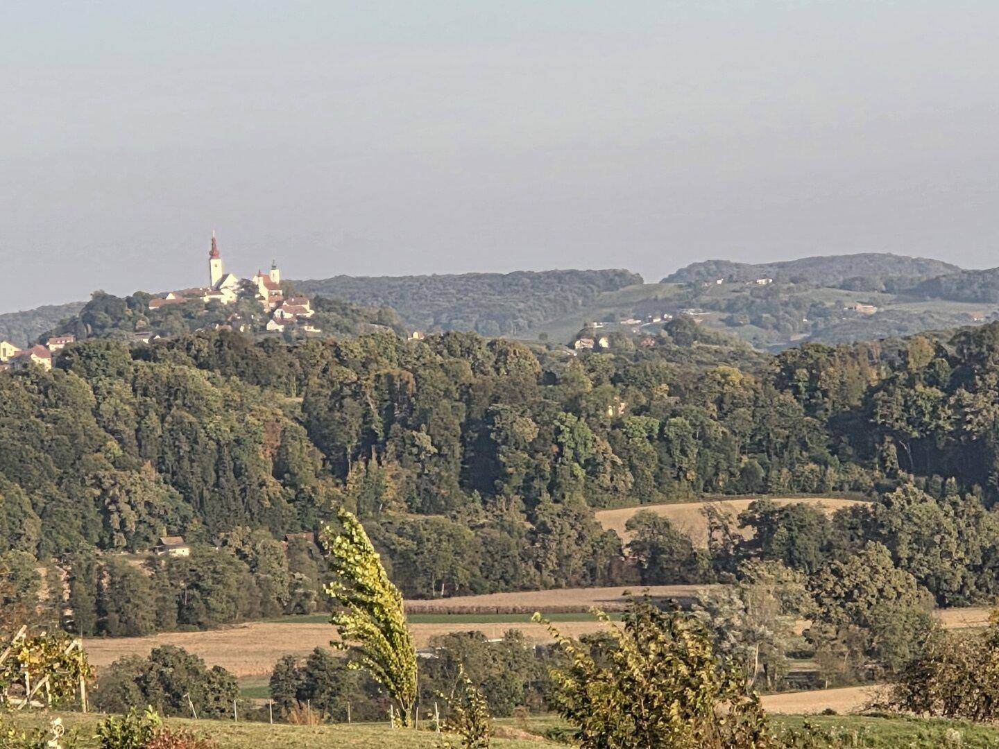 Malerischer Blick auf eine hügelige Landschaft mit einem Dorf in der Ferne.