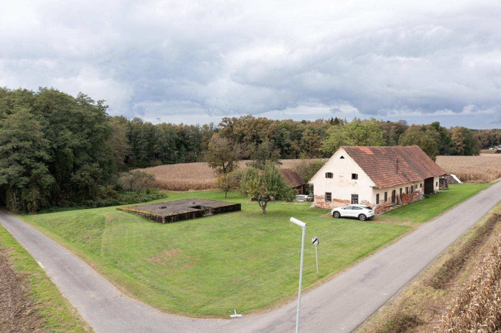 Weitläufiges Grundstück mit einem älteren Wohnhaus und einem Nebengebäude in ländlicher Umgebung.