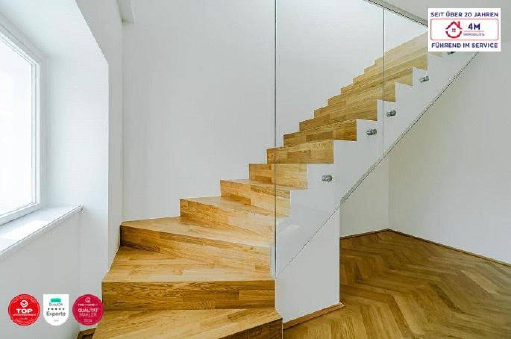 Elegante Holztreppe mit moderner Glasbrüstung, die verschiedene Ebenen verbindet.