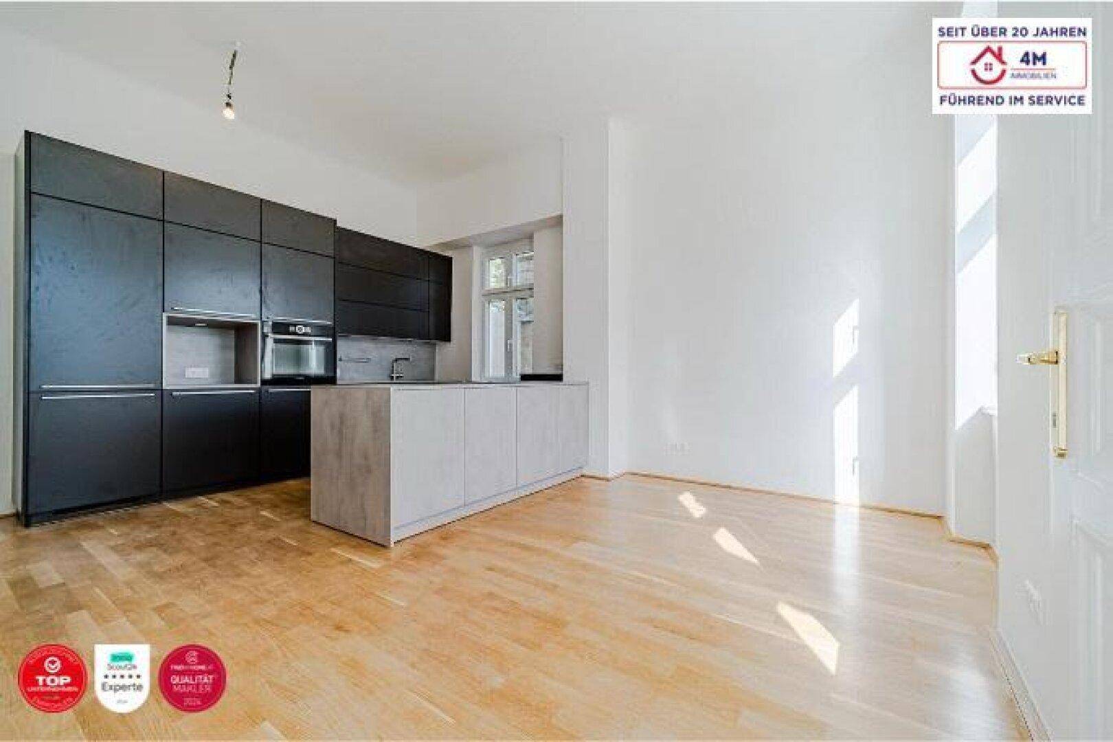 Moderne offene Küche mit dunklen Schränken und heller Kücheninsel in einem geräumigen Zimmer.