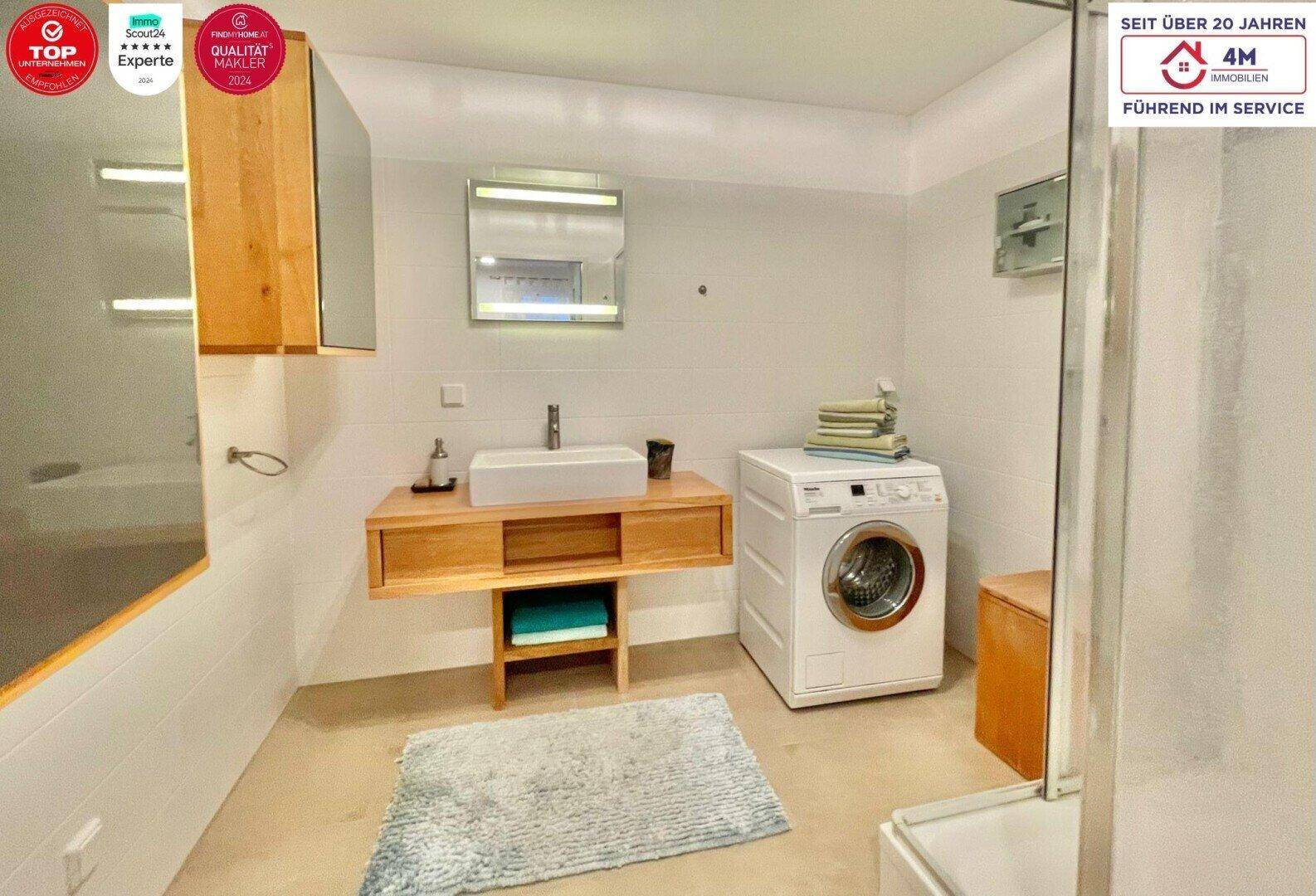 Modernes Badezimmer mit Waschmaschine, Holzwaschtisch und Dusche, praktisch und funktional gestaltet.
