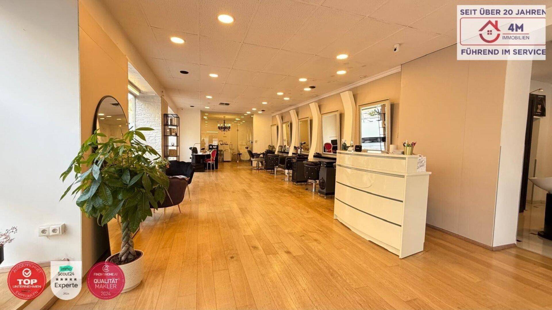 Weitläufiger Friseursalon mit Holzboden, vielen Spiegeln und Arbeitsplätzen, beleuchtet durch Deckenstrahler und Tageslicht.