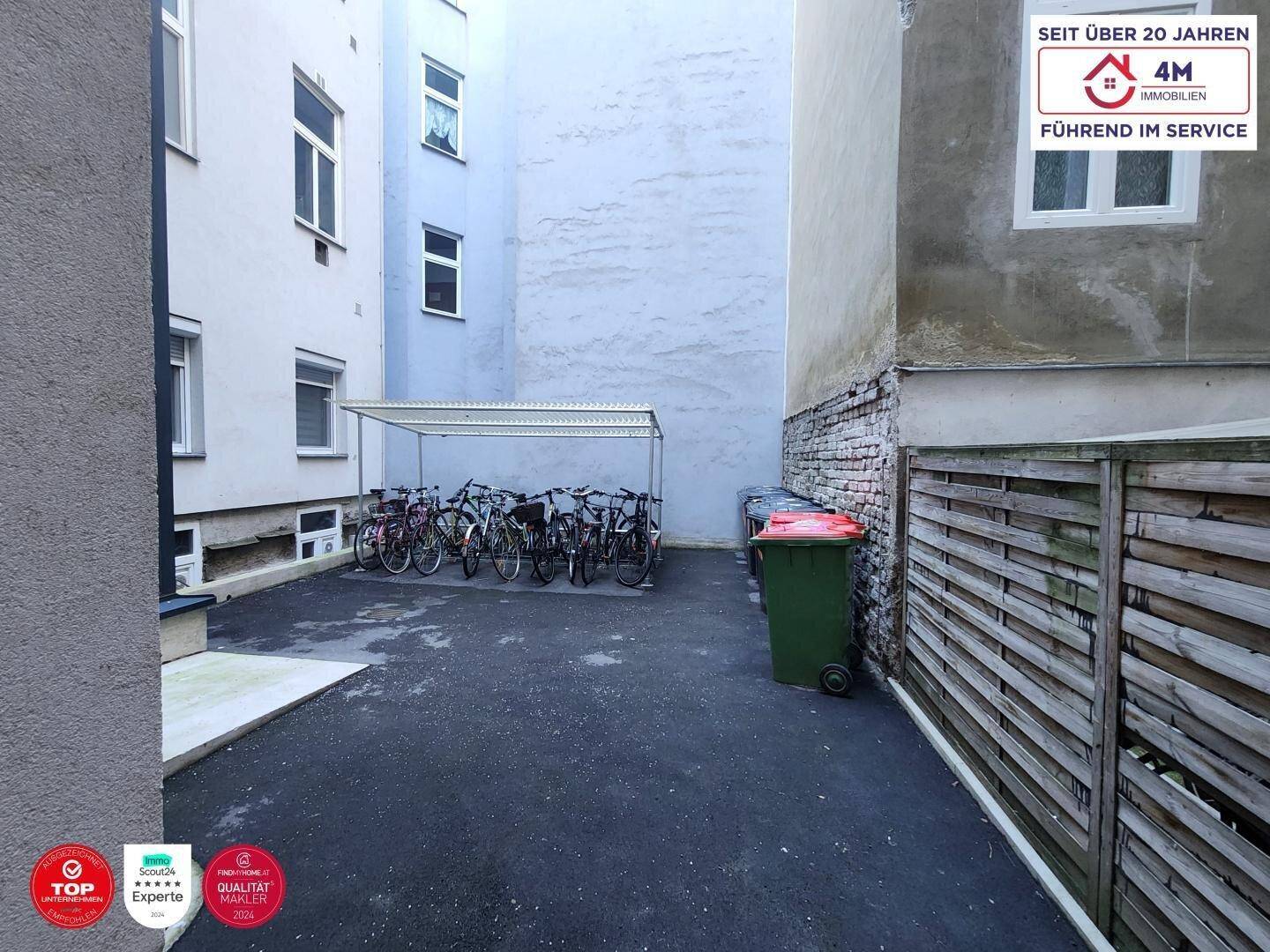 Innenhof zwischen Gebäuden mit Fahrradabstellplatz und Mülltonnen.