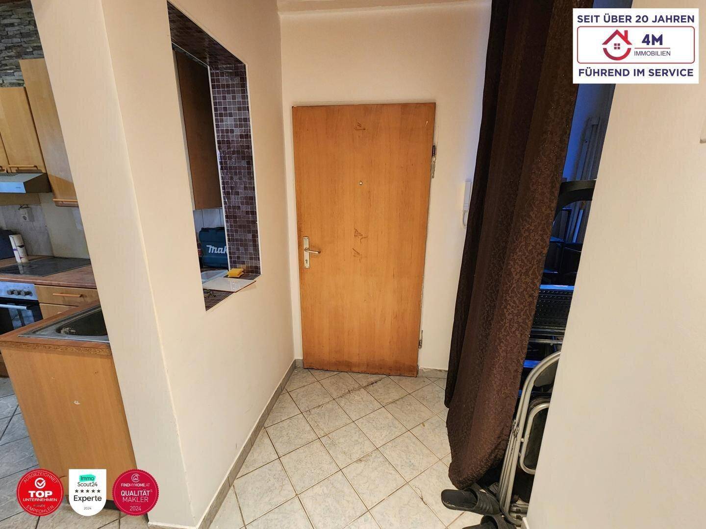 Eingangsbereich mit Fliesenboden und Zugang zur Küche, bietet einen praktischen Durchgang.