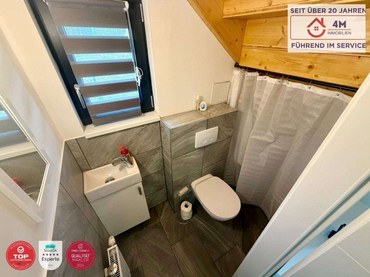 Kleines Gäste-WC im Dachgeschoss mit schrägen Wänden und Fenster.