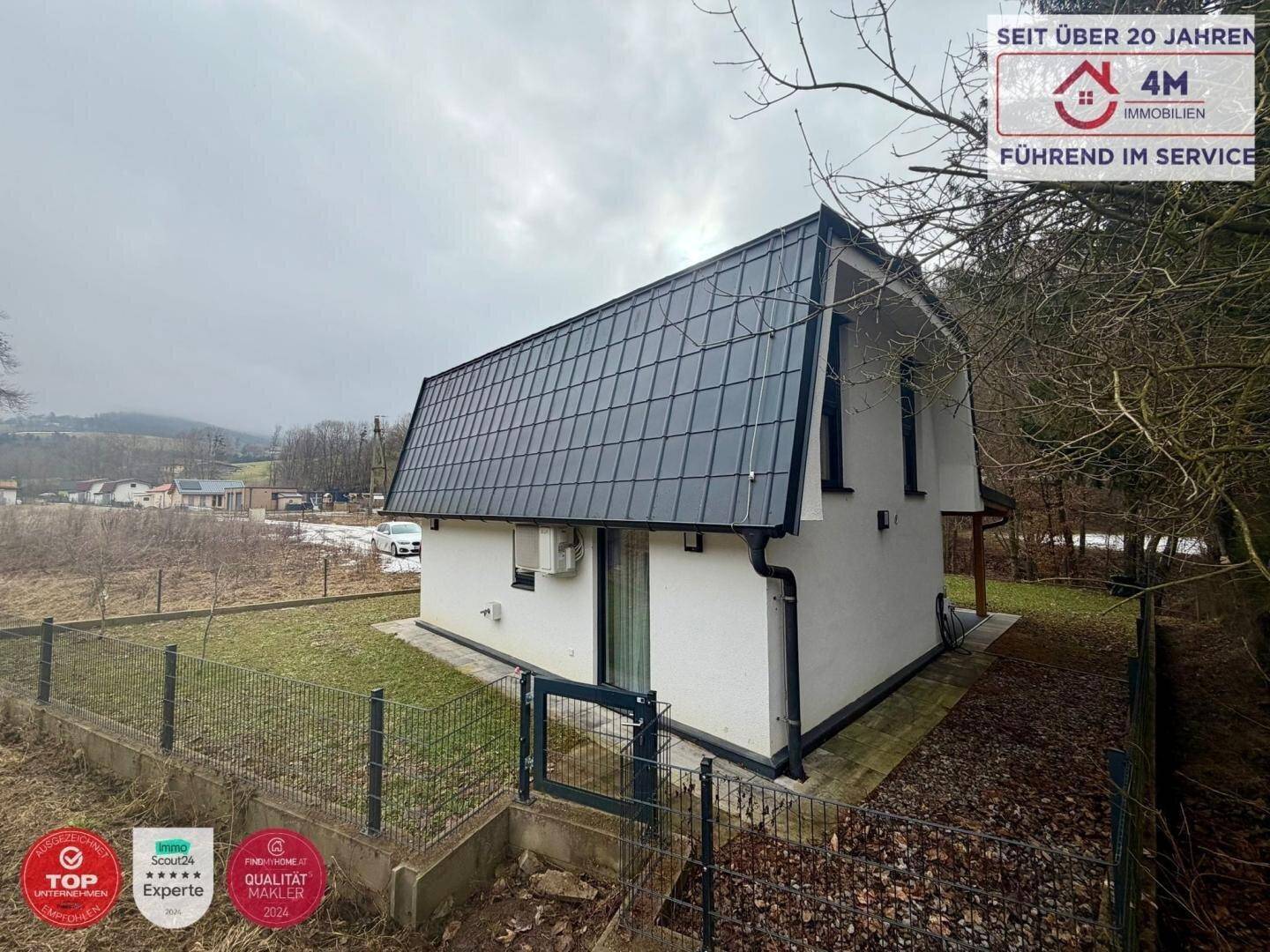 Rückansicht des modernen Hauses mit dunklem Dach und Blick auf die Umgebung.