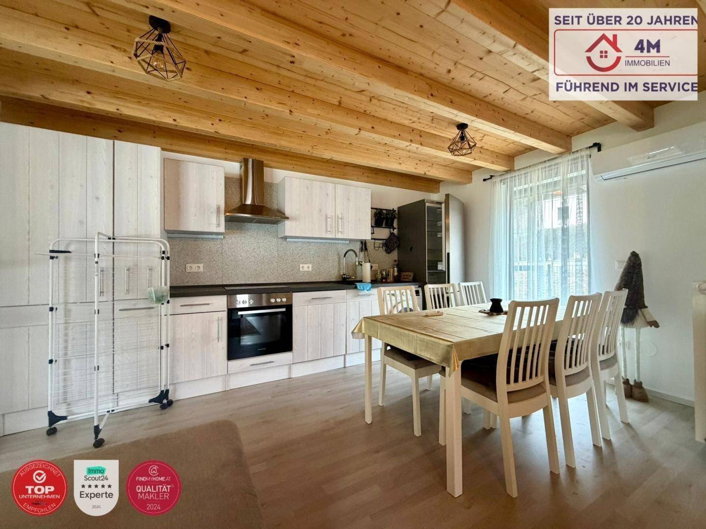 Moderne Wohnküche mit hellen Schränken, Holzbalkendecke und Essbereich.
