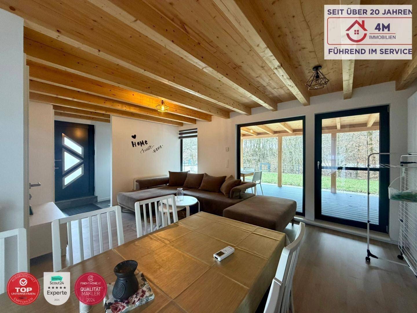 Offener Wohn- und Essbereich mit großen Fenstern und direktem Zugang zur überdachten Terrasse.