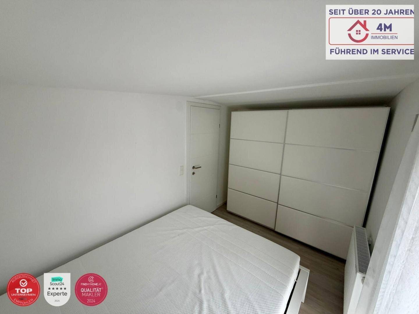 Schlafzimmer mit Doppelbett und großem weißen Kleiderschrank.