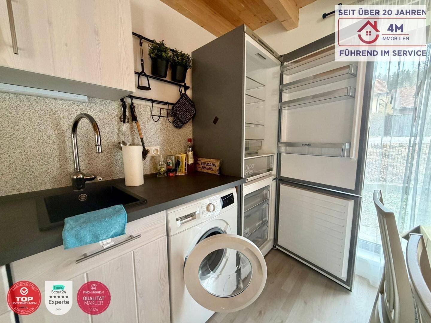Detailansicht der modernen Küche mit Spüle, Waschmaschine und großem Kühlschrank.