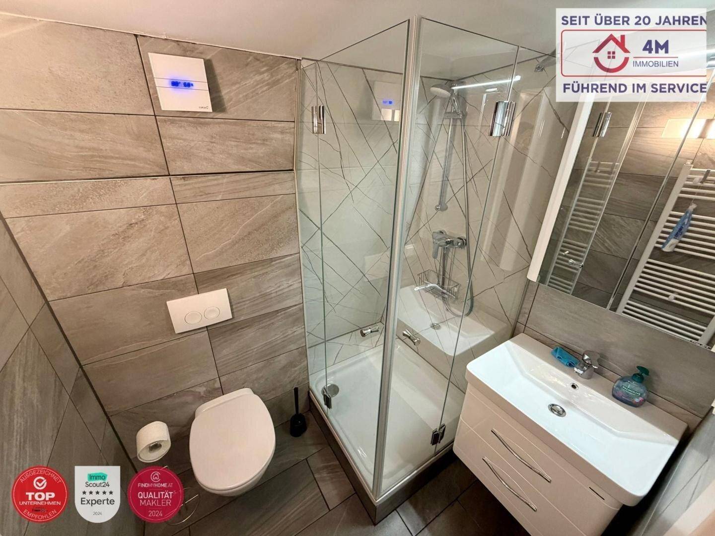 Modernes Badezimmer mit Duschkabine, WC, Waschbecken und beheiztem Handtuchhalter.