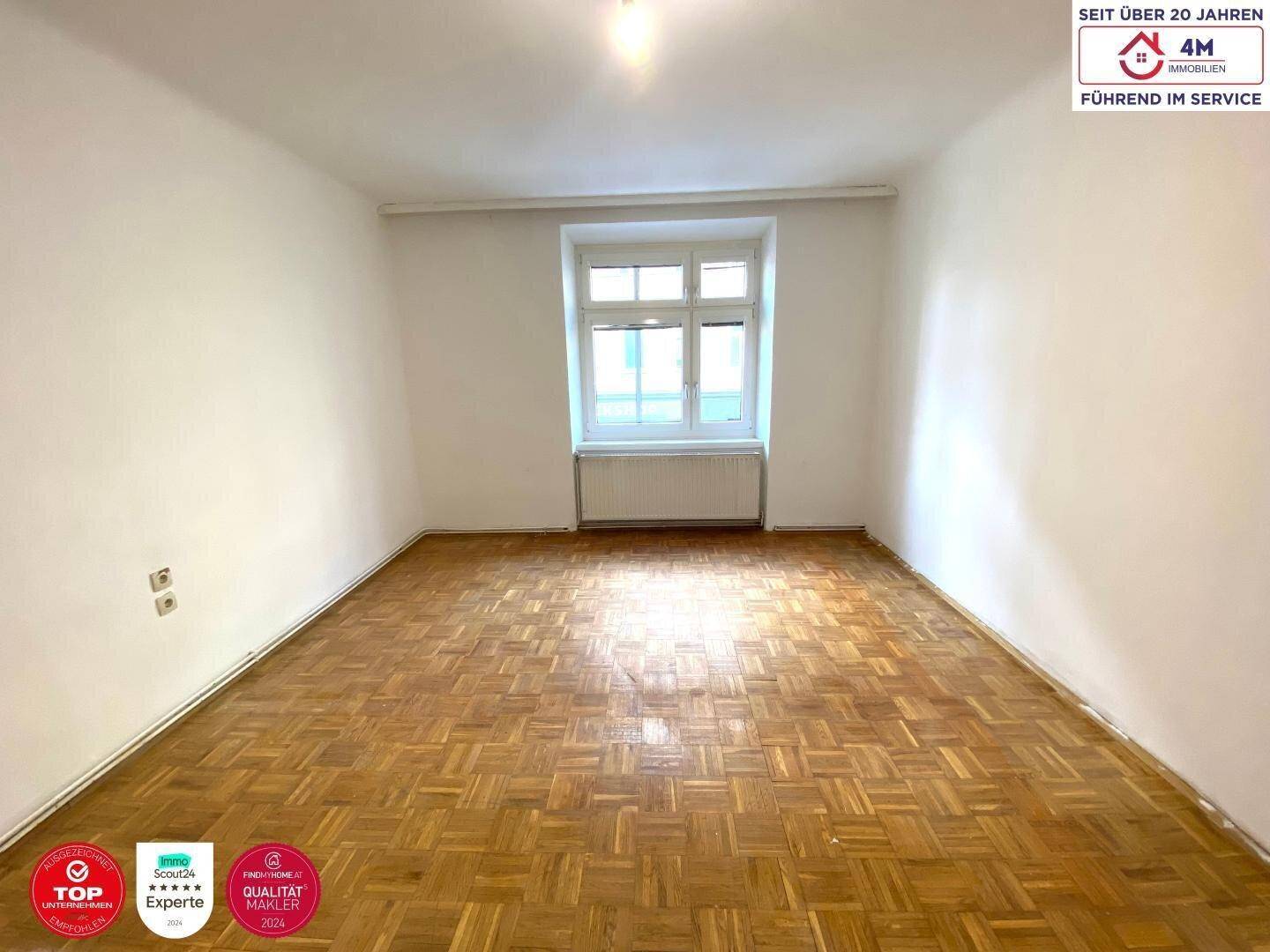 Geräumiges, helles Zimmer mit klassischem Fischgrätparkett und viel Tageslicht.